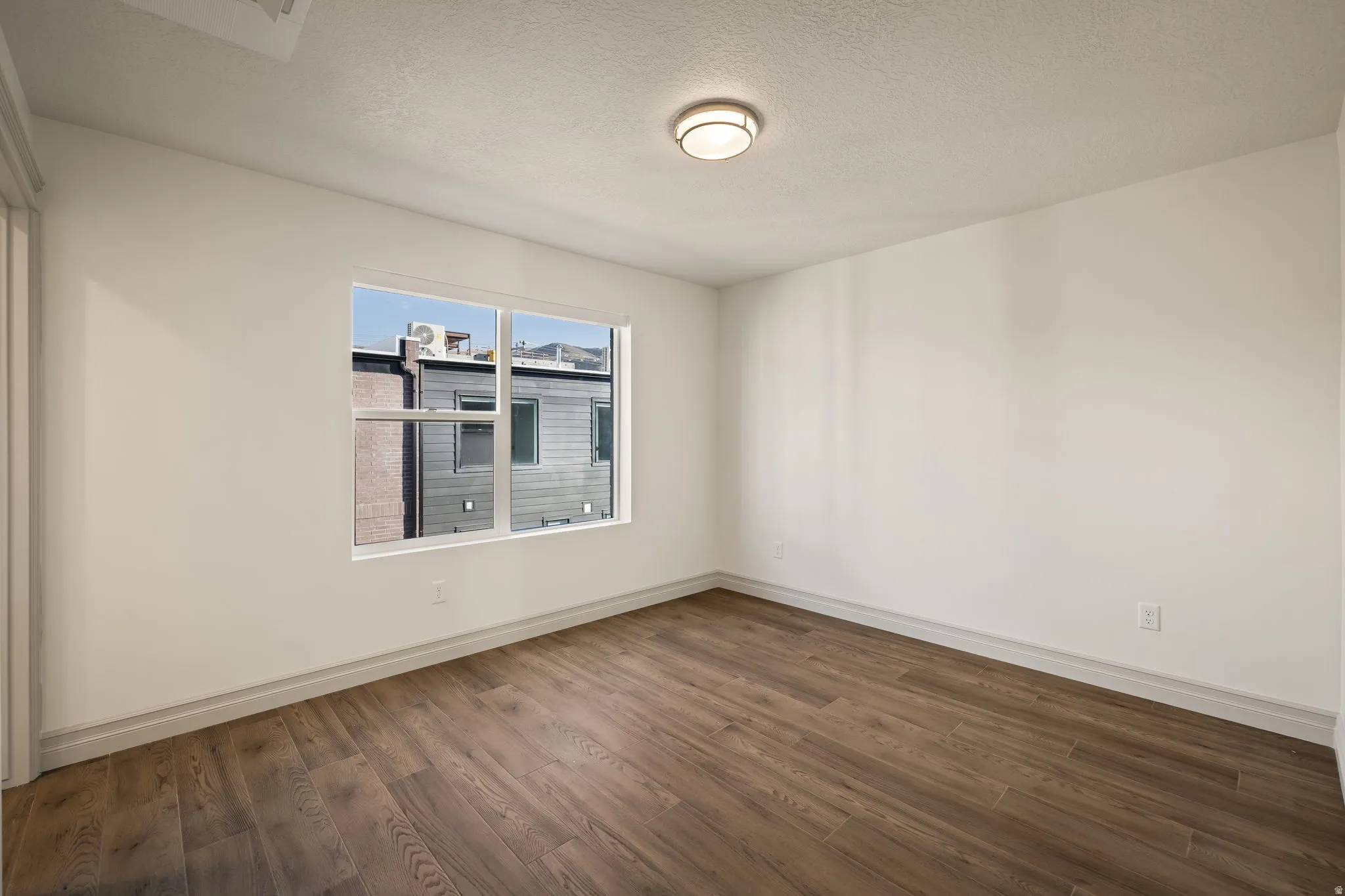 Wood-finish flooring, white painted walls, and a multi-pane window