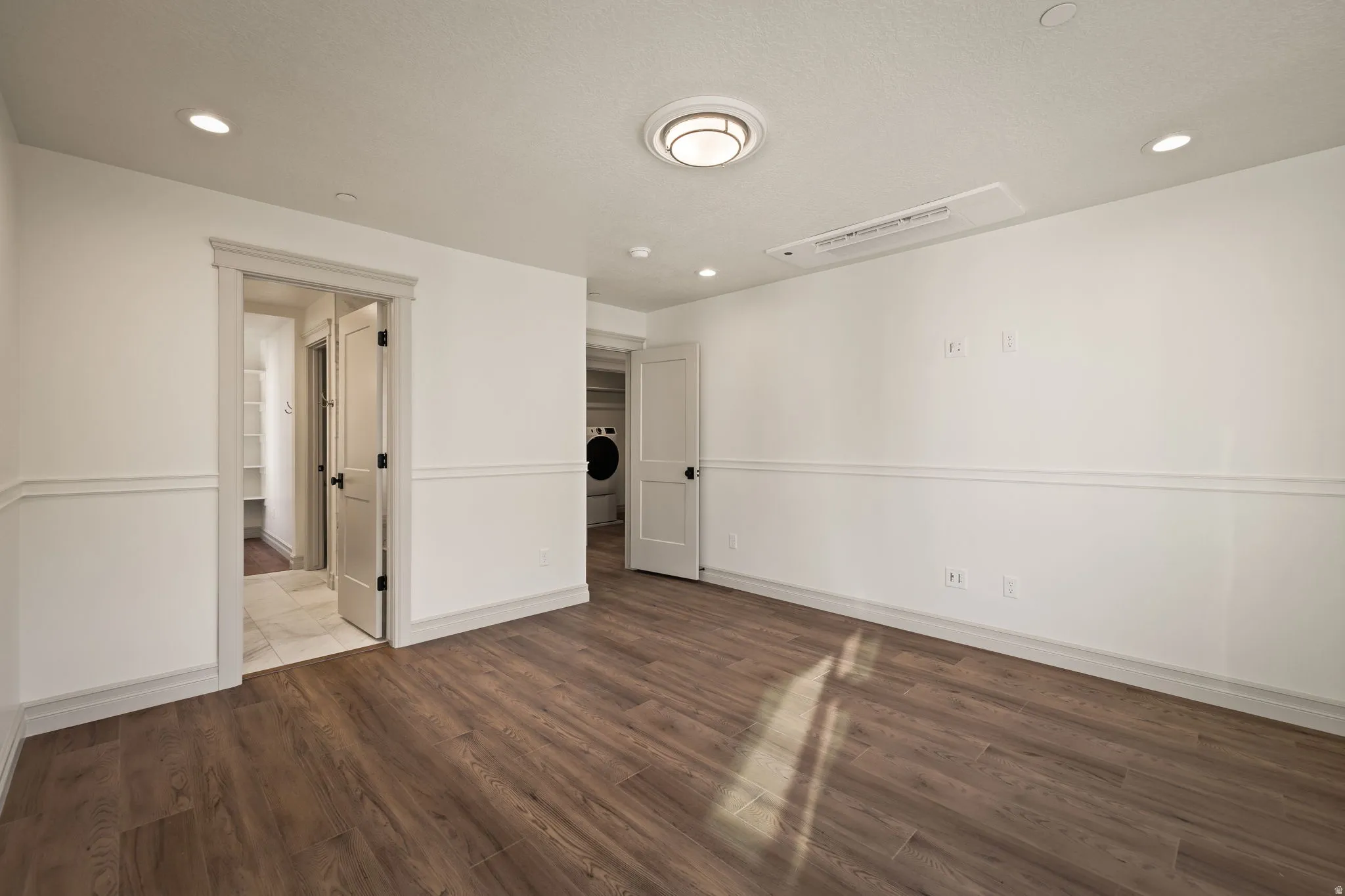 Wood-finish flooring, recessed lighting, chair rail molding, and a flush-mount ceiling fixture