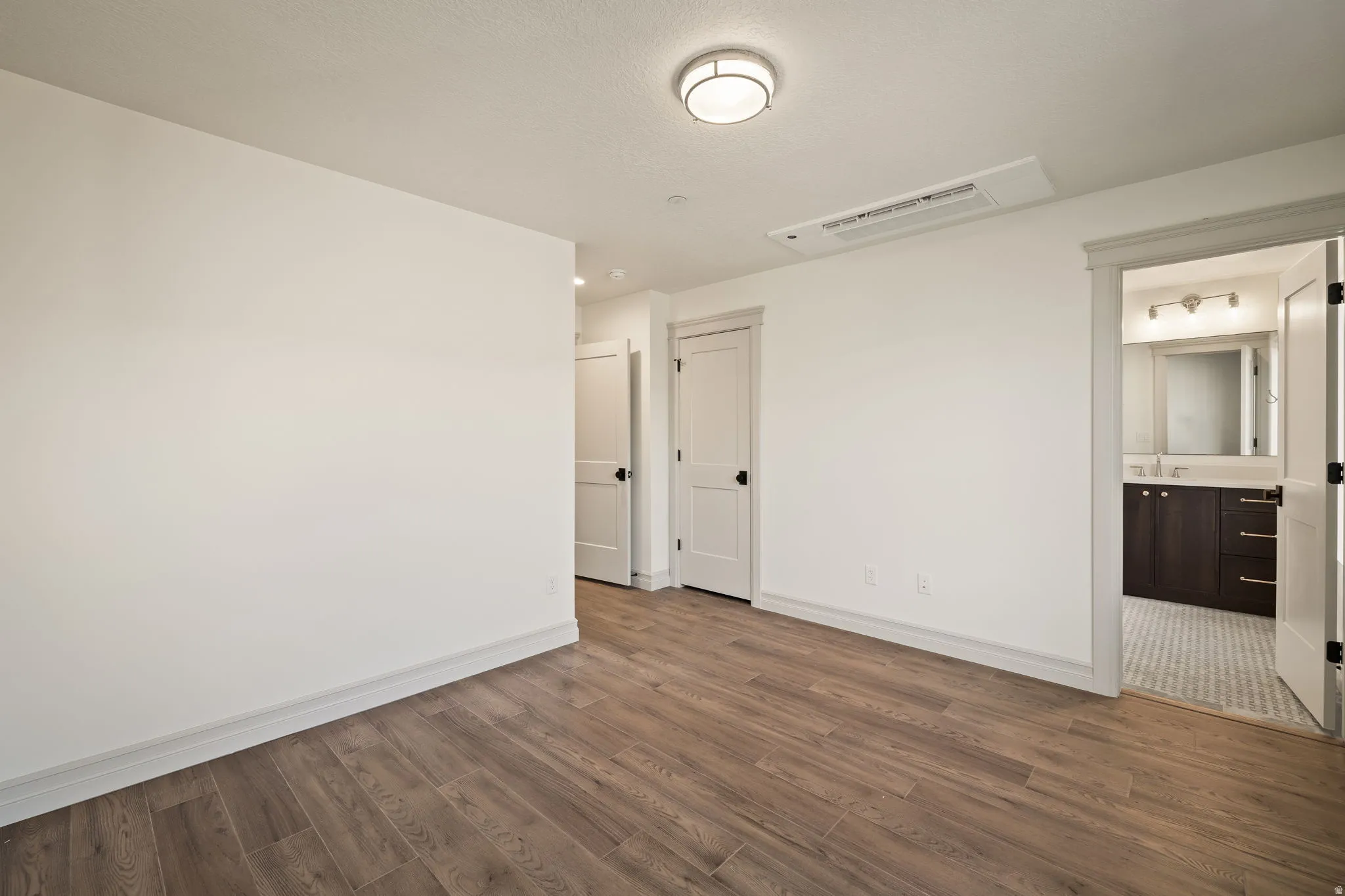 Wood-finish flooring, recessed ceiling lighting, and crisp white walls