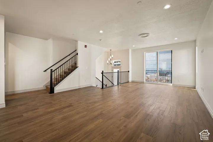 Expansive living area with wood-finish flooring, recessed lighting, and a sliding glass door leading to a balcony