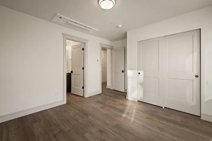 Wood-finish flooring throughout, white walls, flush-mount ceiling light, and white paneled doors