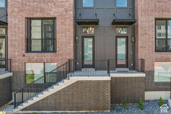Brick facade with contrasting dark brick lower level, concrete stairs, and black metal railings