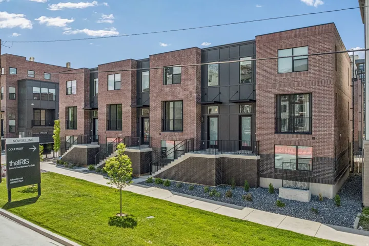 Brick and dark panel exterior, multiple large windows, landscaped grounds, and a sidewalk