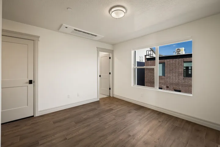 Wood-finish flooring, white walls, and a large window