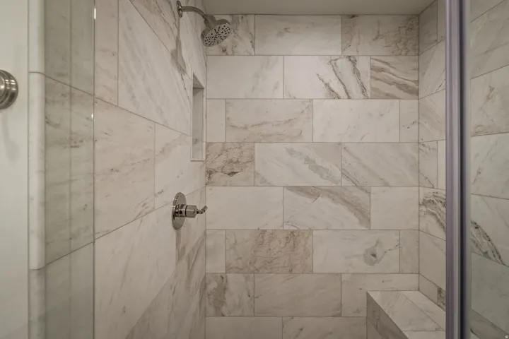 Tiled shower stall featuring a built-in niche, integrated bench, and brushed nickel fixtures