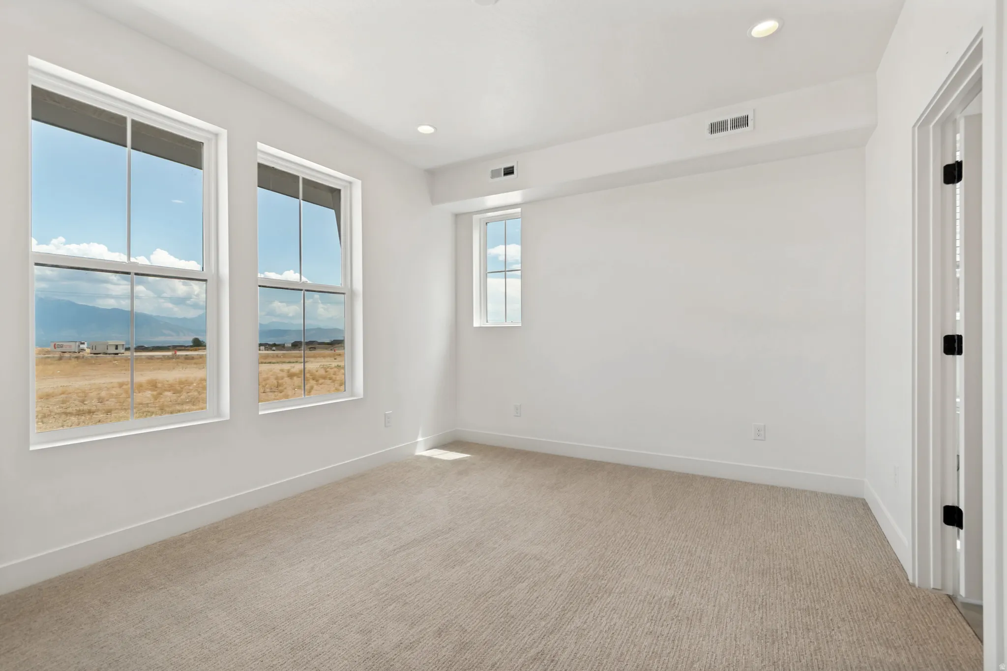 Recessed lighting, light-toned carpet flooring, white painted walls, and white window trim