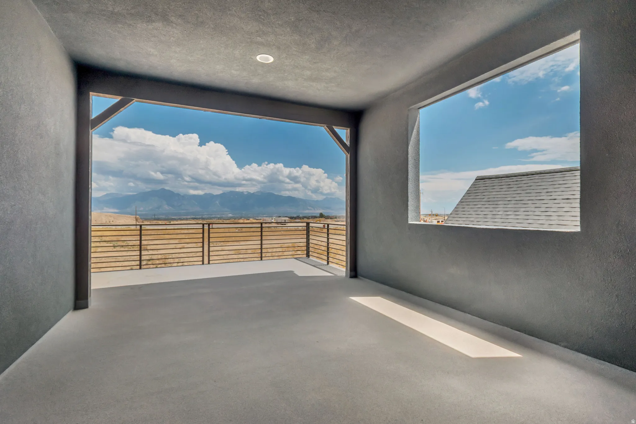 Expansive covered patio featuring a concrete floor, recessed lighting, and metal horizontal slat railing