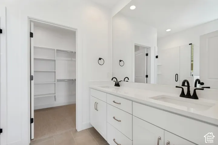Dual vanity with white cabinetry, integrated sinks, black fixtures, and a large wall mirror