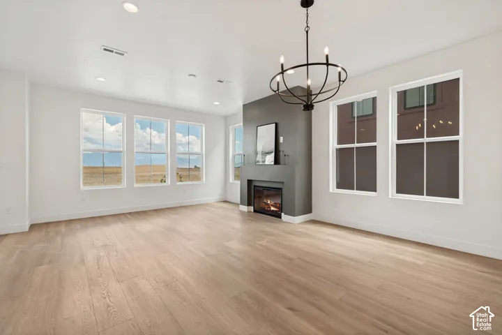 Spacious room featuring light wood-finish flooring, a contemporary fireplace with a dark gray surround, and multiple large windows