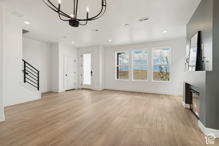 Recessed lighting, wood-finish flooring, staircase with metal railing, contemporary fireplace, and multiple windows