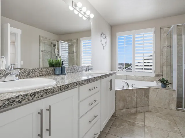 Ensuite bathroom with dual vanity, both a tub and an enclosed shower.