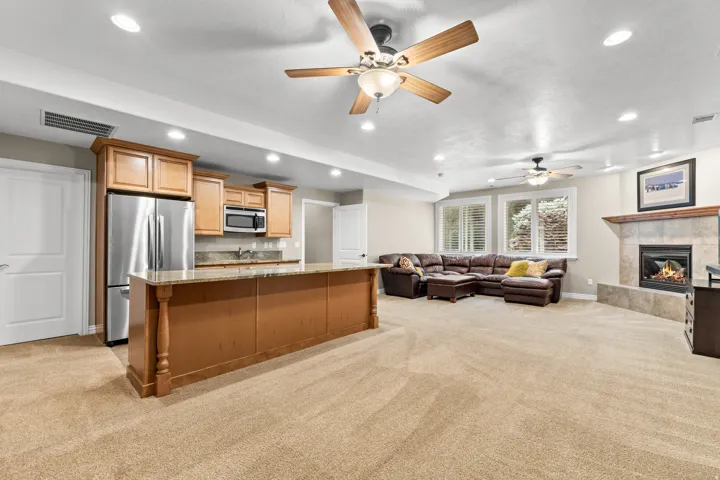 Open-concept living space featuring a fireplace with a wood mantle, recessed lighting, and ceiling fans