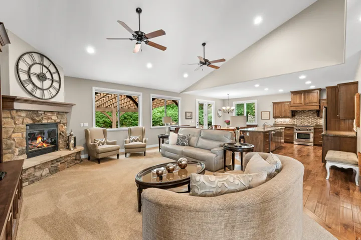 Vaulted ceilings, a stone-clad fireplace, recessed lighting, and wood-finish flooring