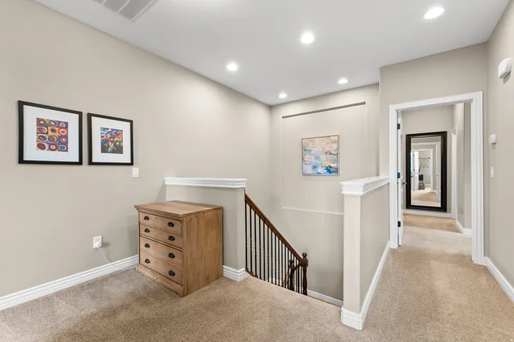 Carpeted hallway with recessed lighting, white trim, and a dark wood-finish staircase