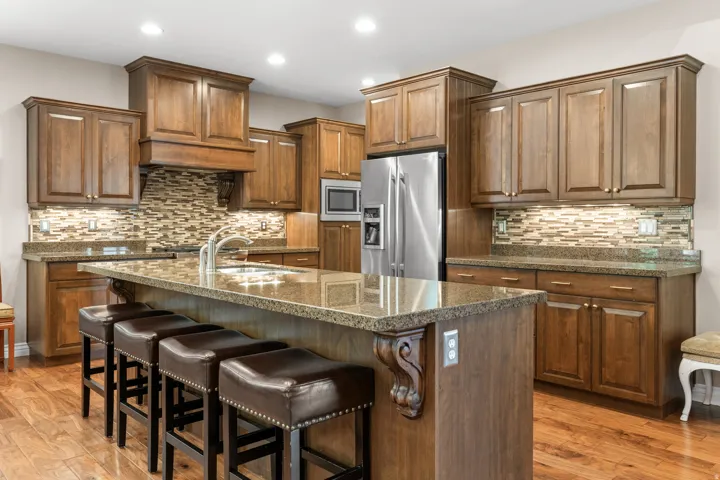 Hardwood flooring, wood cabinetry, granite countertops, stainless steel appliances, and a tiled backsplash
