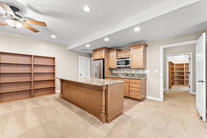 Kitchenette featuring wood-finish cabinetry, stainless steel appliances, and a stone countertop