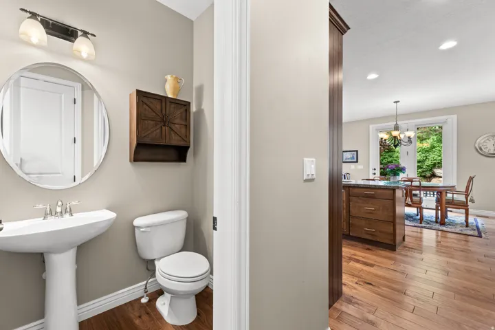 Pedestal sink with chrome faucet, round wall mirror, and wall-mounted vanity light fixture