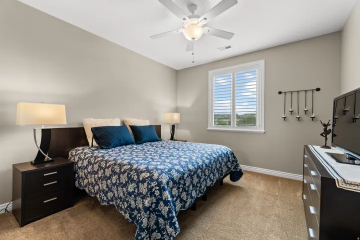 Window with plantation shutters, ceiling fan with integrated lighting, neutral wall paint, and carpet flooring