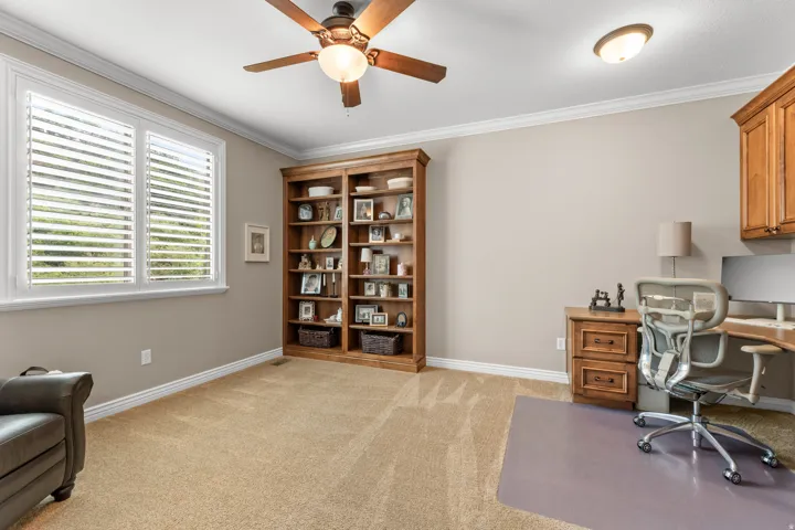 Built-in wooden shelving, dual windows with plantation shutters, ceiling fan with integrated lighting, recessed lighting, and crown molding