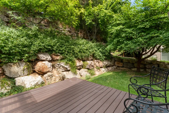 Outdoor deck with wood-finish planks, flanked by a natural rock retaining wall