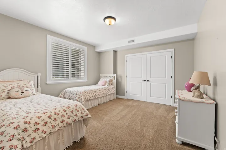 Neutral wall paint, carpet flooring, window with white shutters, white double-panel doors, and a ceiling light fixture