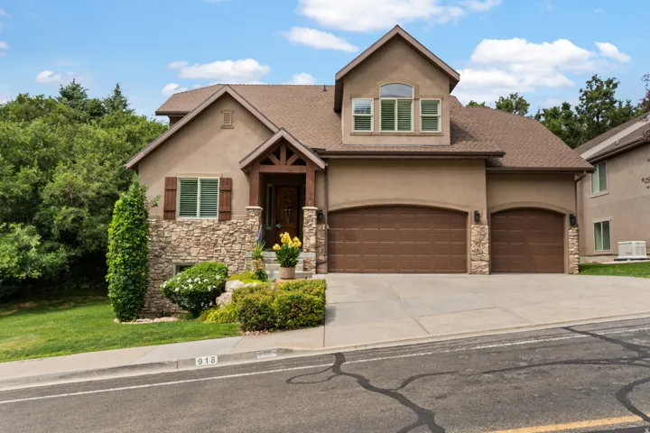 Stucco exterior with stone accents, covered entry, and attached two-car garage