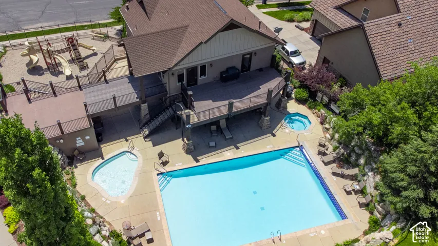 Community clubhouse, large outdoor  swimming pool with integrated steps, adjacent hot tub, and a separate kidney-shaped pool