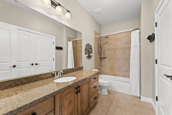 Vanity with a granite-style countertop, wood-finish cabinetry, and a full-width mirror