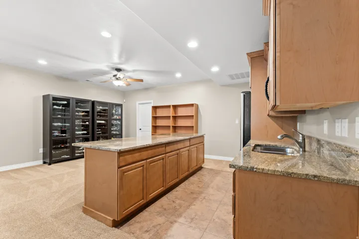 Spacious room featuring a central island with integrated cabinetry and a stone countertop, recessed lighting, and a ceiling fan