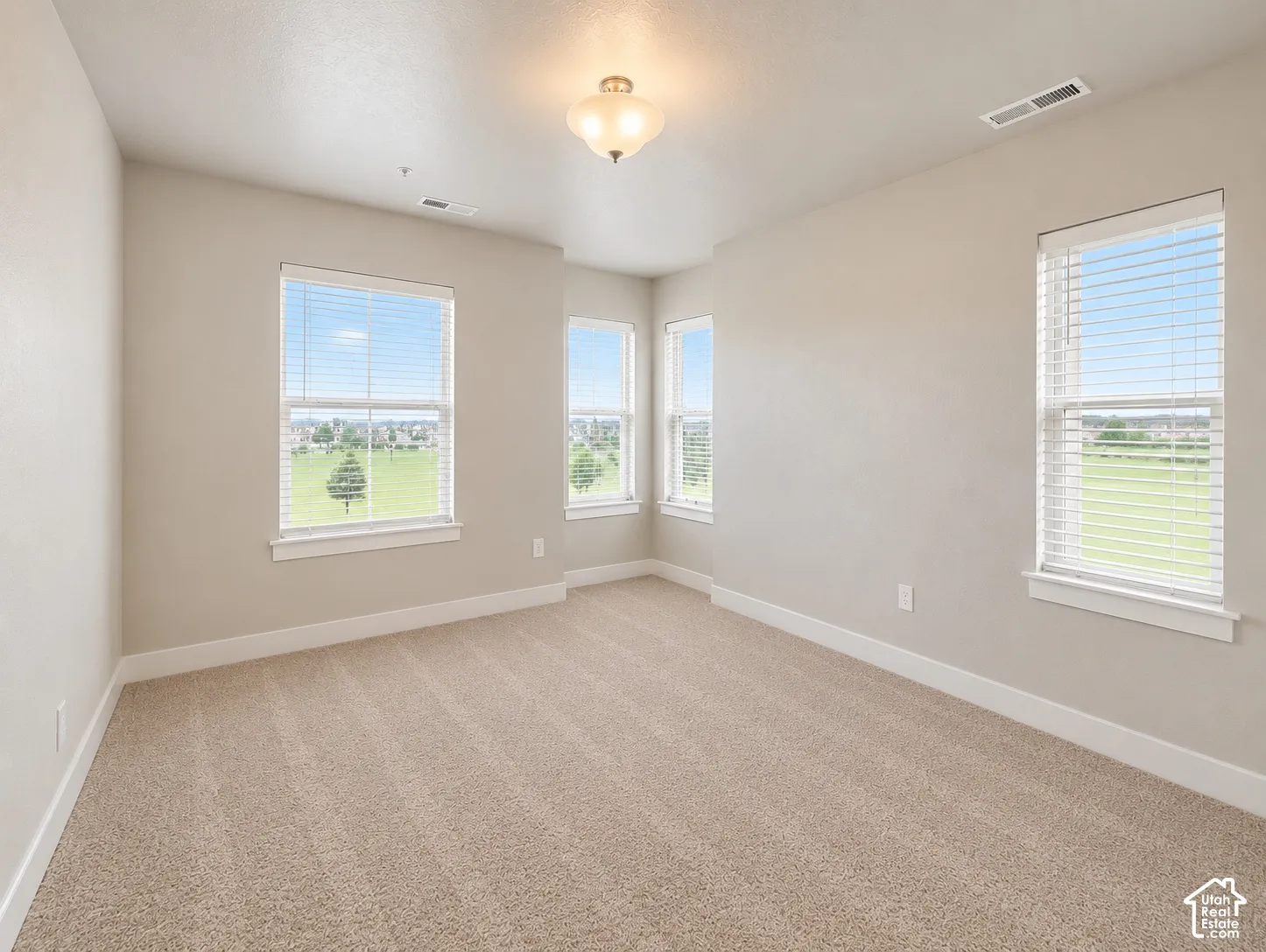 Primary room featuring pop out nook. Multiple windows, neutral wall tones, textured carpeting, recessed lighting, and a ceiling-mounted light fixture