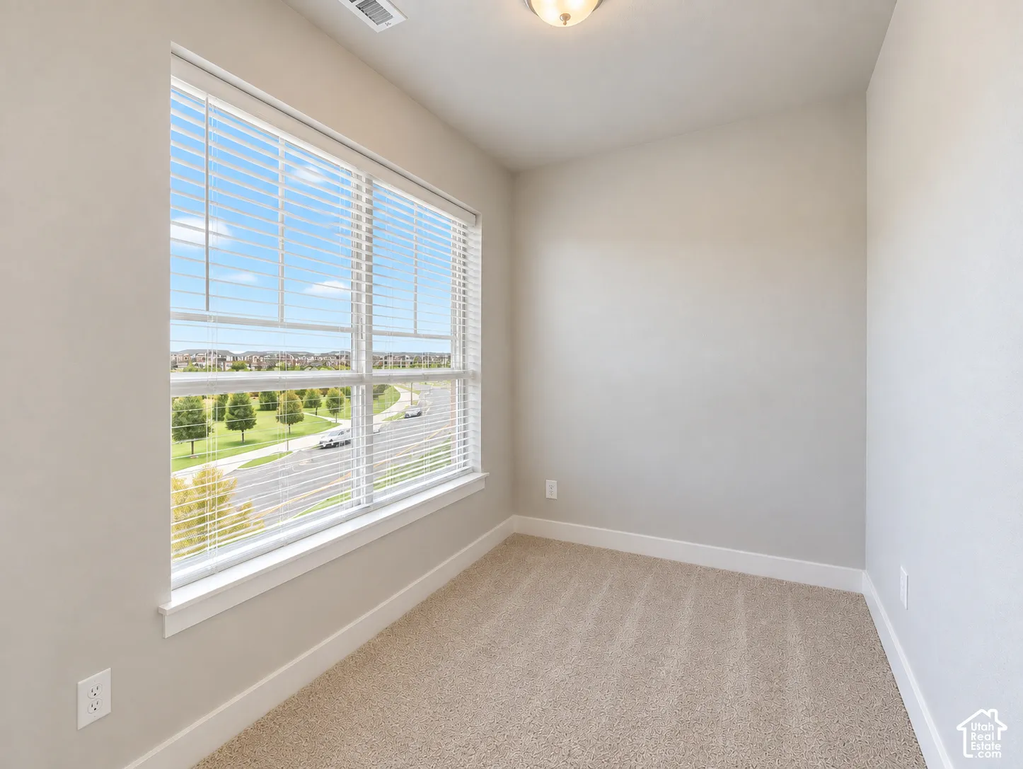 Main living nook. Spacious room featuring broad windows with horizontal blinds, neutral wall tones, and plush carpeting