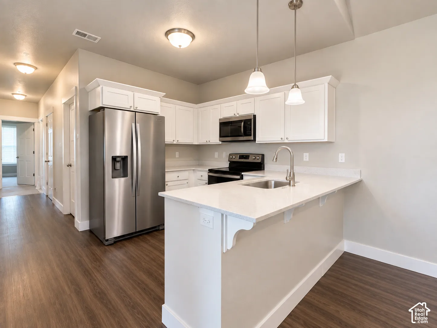 Kitchen featuring white cabinetry, stainless steel appliances, white countertops, and wood-finish flooring
