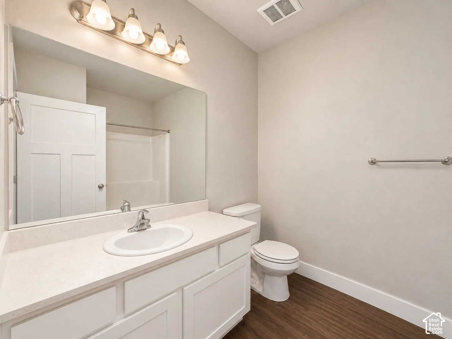 Bathroom 2 featuring a single vanity with an integrated sink, white cabinetry, a large wall-mounted mirror, and wood-finish flooring