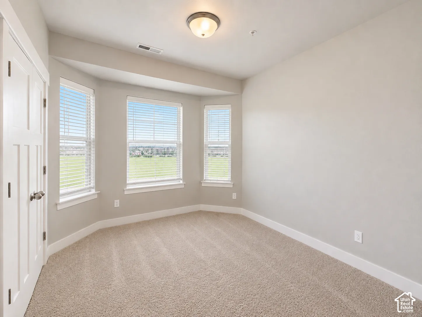 Bedroom 2. Window with three windows, neutral-toned walls, neutral-toned carpet, and a flush mount light fixture