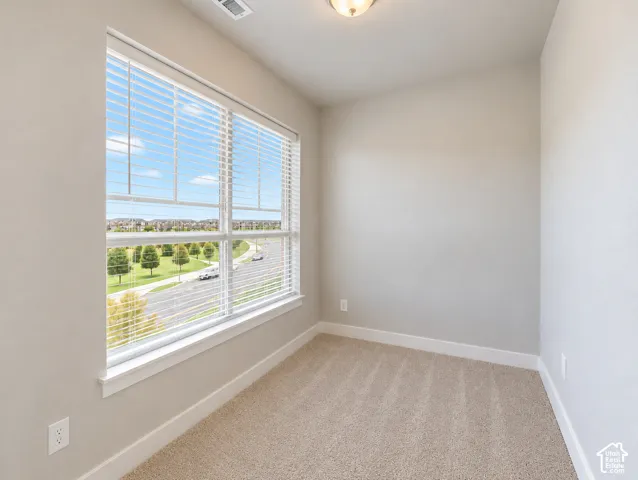 Main living nook. Spacious room featuring broad windows with horizontal blinds, neutral wall tones, and plush carpeting