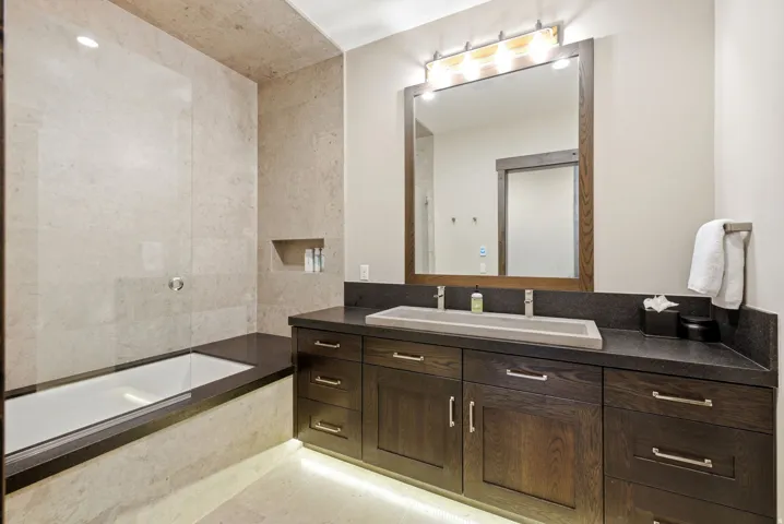 Built-in bathtub with a clear glass enclosure and tile surround
