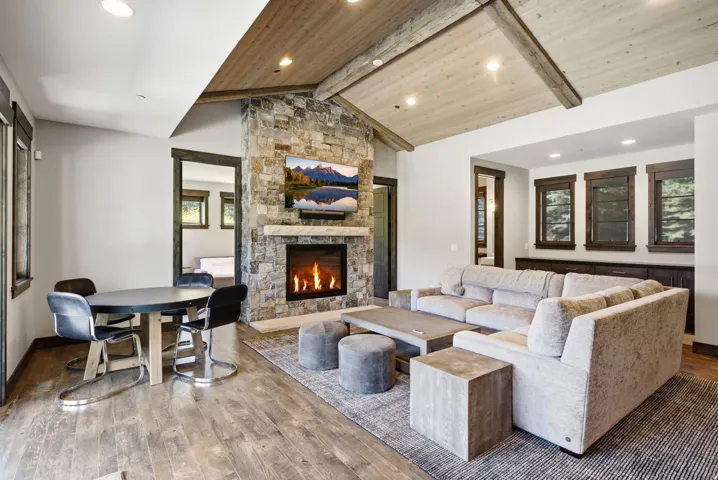 Stone-clad fireplace with a hearth, wood-finish flooring, and a vaulted wood-paneled ceiling with exposed beams