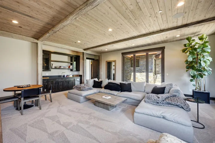 Wood-plank ceiling with exposed beams, recessed lighting, and a built-in wet bar with dark cabinetry
