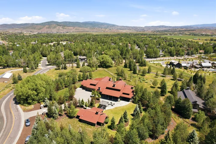 Expansive property featuring a red tile roof, mature trees, a private driveway, and mountain scenery