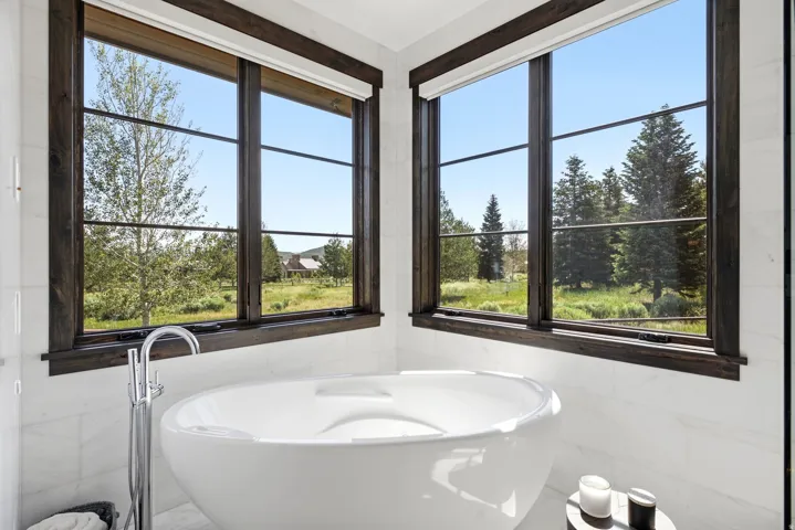 Freestanding soaking tub with a floor-mounted faucet, set against white marble-look tile walls