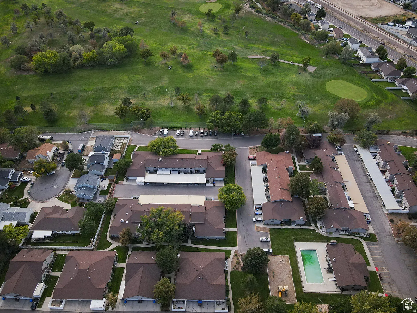Aerial perspective showcasing multiple residential buildings with brown roofs, adjacent to a green golf course