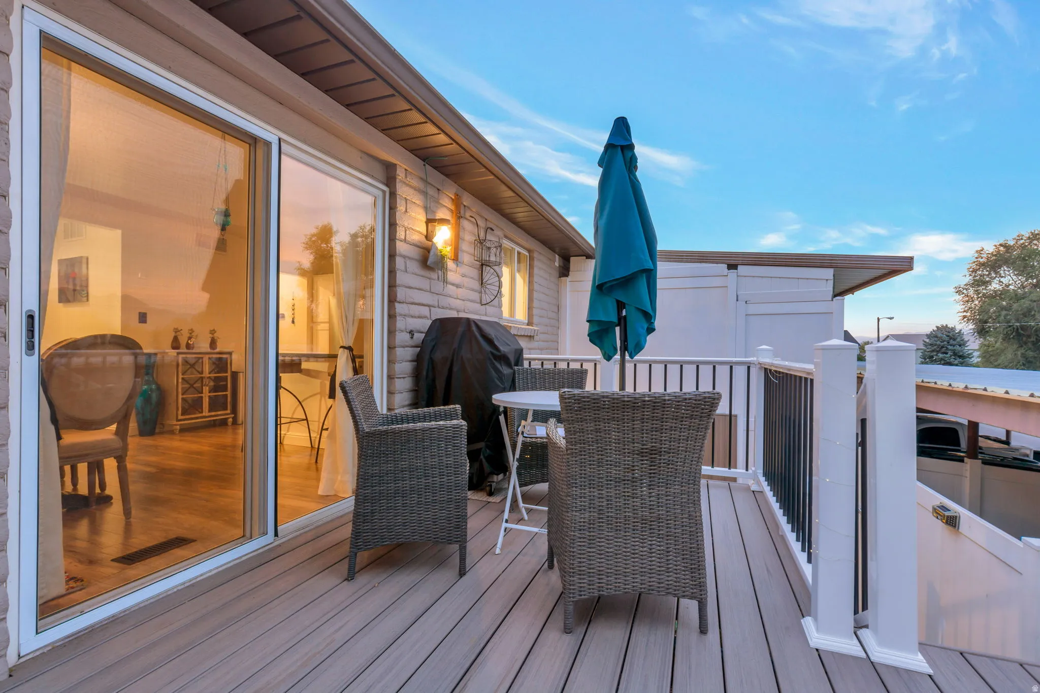 Expansive deck featuring composite decking, white railing with black balusters, and a sliding glass door