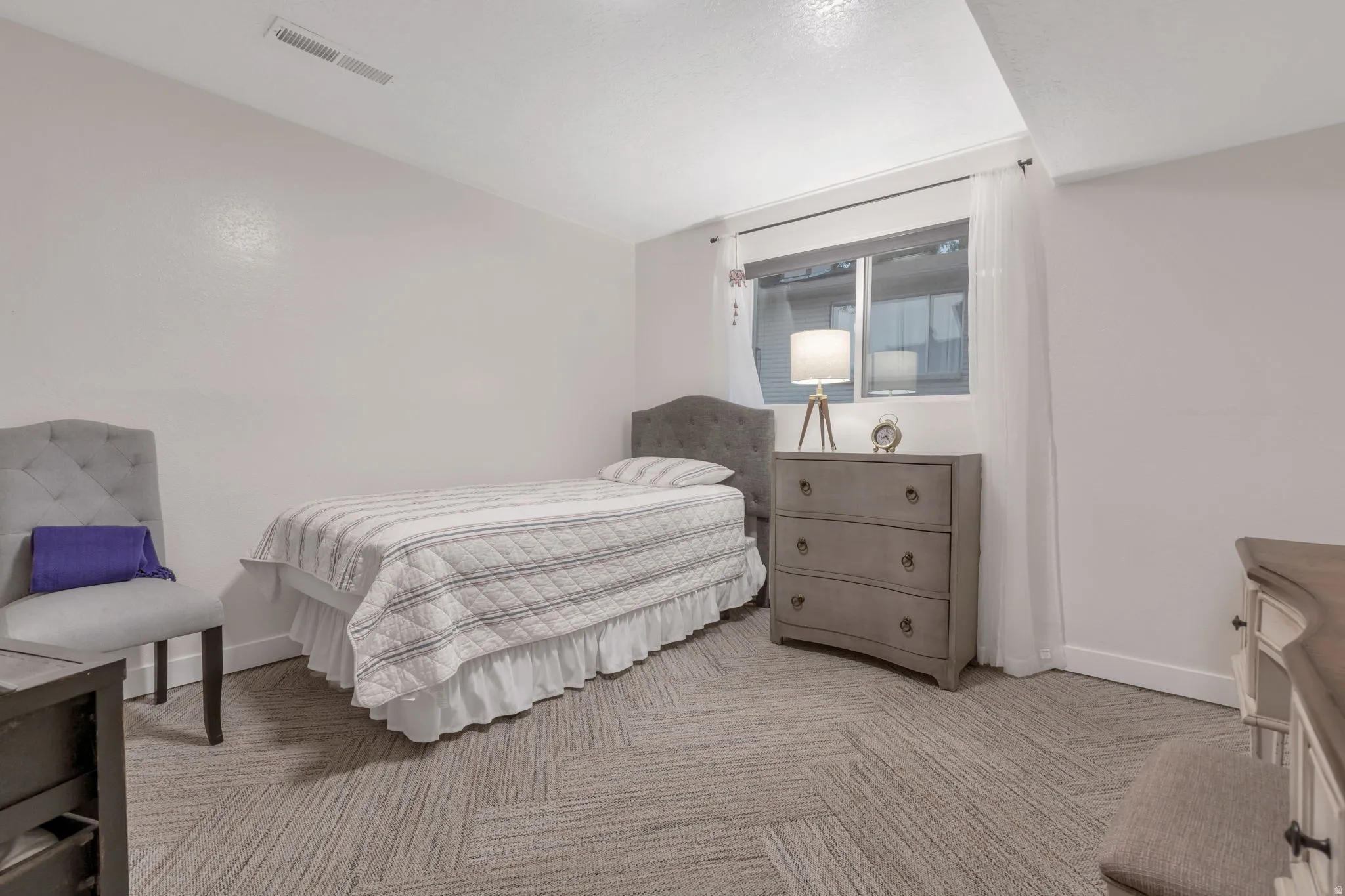 Recessed lighting, window with white sheer curtains, and patterned carpet