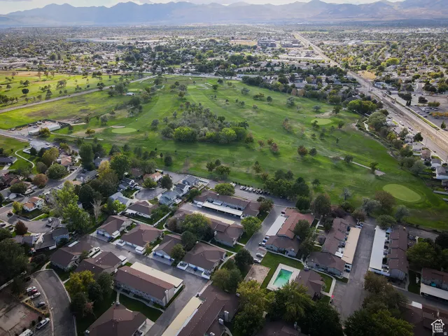 Expansive green spaces with mature trees, residential properties, and distant mountains