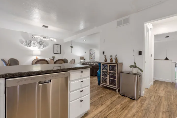 Kitchen island with a dark countertop and a stainless-steel dishwasher, complemented by wood-finish flooring