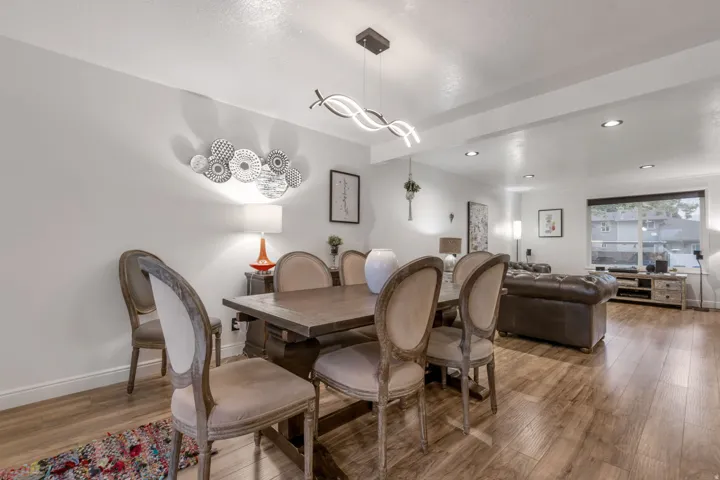Open-concept living area featuring wood-finish flooring, recessed lighting, and a modern linear chandelier