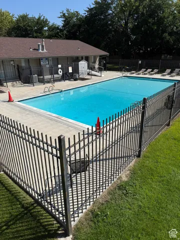 Fenced swimming pool with a surrounding concrete deck and adjacent building