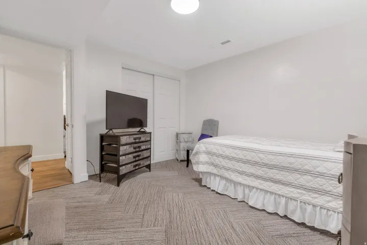 Textured carpet flooring with a patterned design, white painted walls, and a recessed ceiling light