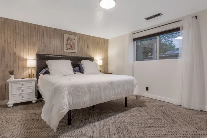 Accent wall featuring vertical wood paneling, recessed lighting, expansive window with roller shade, and patterned carpet flooring
