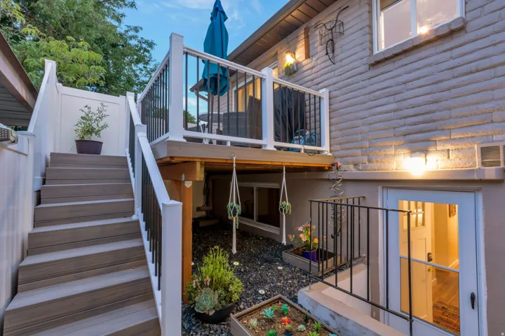 Multi-level outdoor living space featuring a composite deck with white railings, stairs with composite treads, and a lower patio area with dark stone ground cover